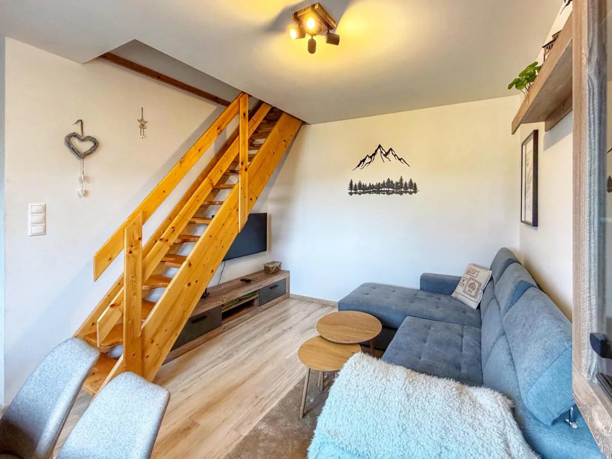 Obývacia izba Apartmánu Tatris s dreveným schodiskom a sivým gaučom